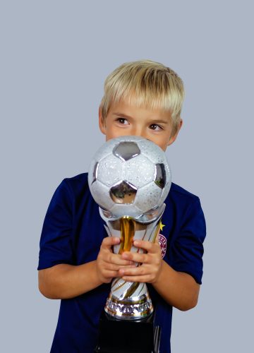 young-soccer-player-in-blue-jersey-holds-winners-cup-after-the-goal-isolated-at-light-background.jpg